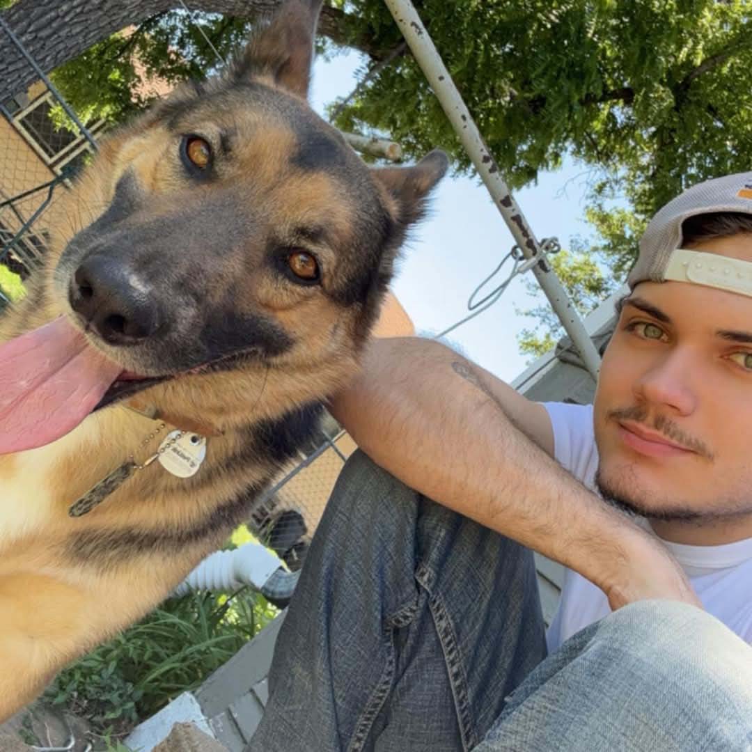 A man kneeling next to a German Shepard.