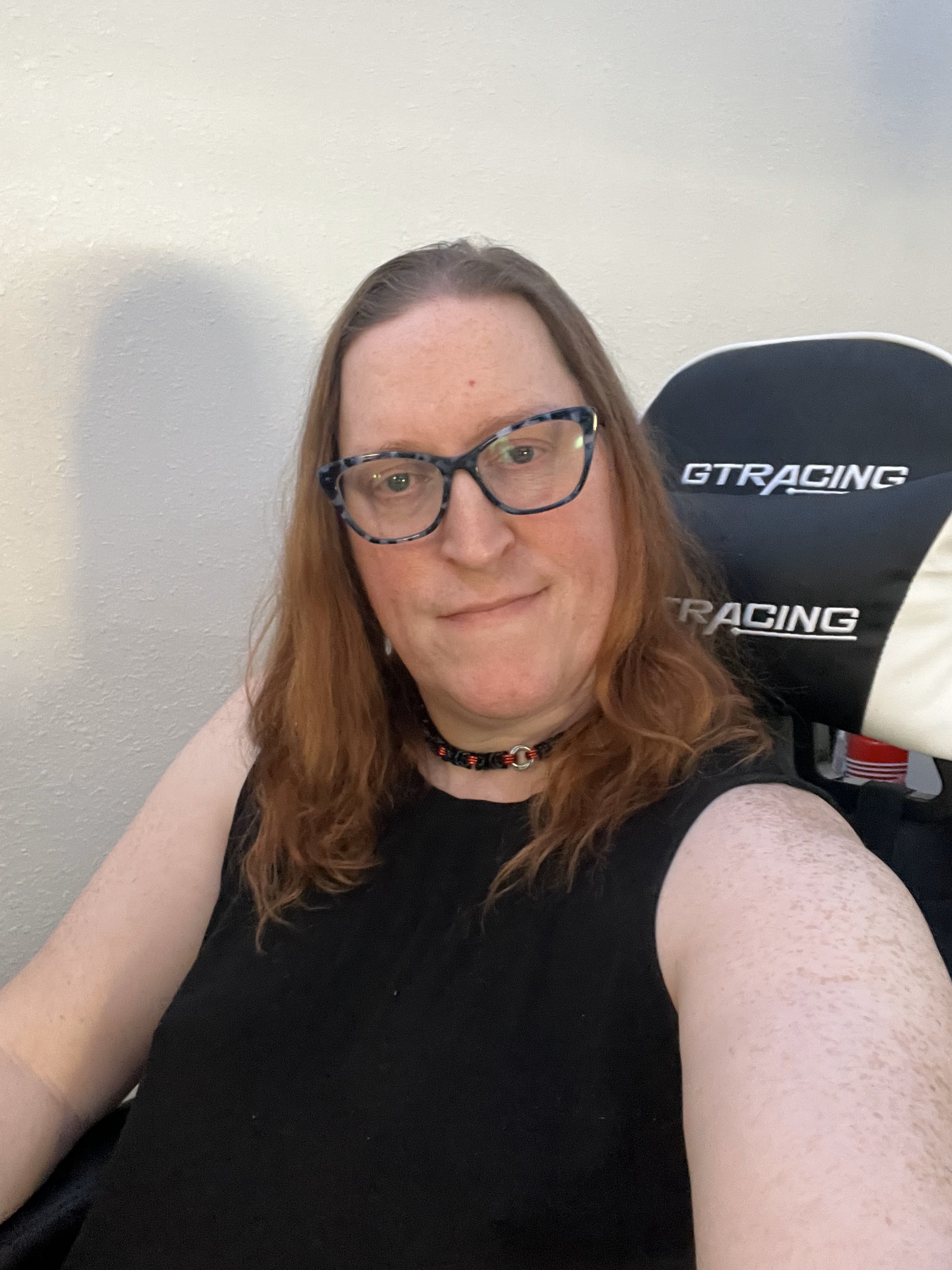 A woman with glasses sitting in a racing chair.